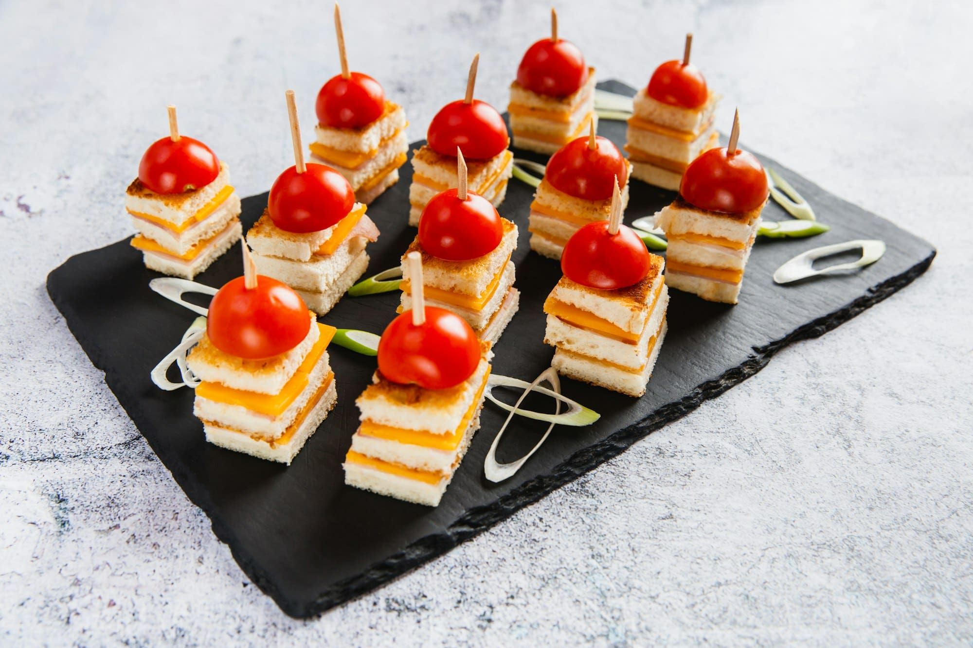 Cheese canapes decorated tomato on black plate