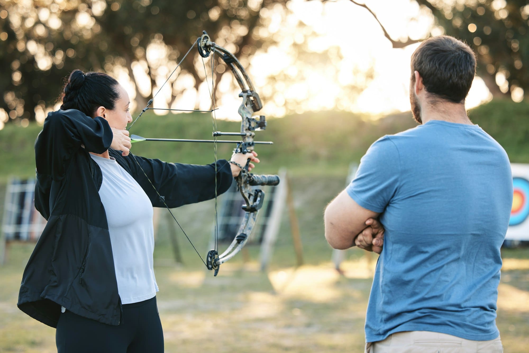 Archery, sports or help with a woman holding a bow and arrow outdoor for target practice with a coa